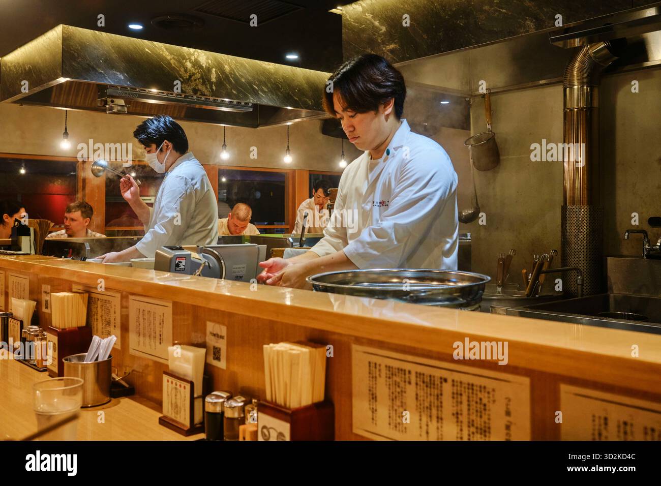 Ramen-Köche bereiten frische Nudeln hinter der Theke in einem Ramen-Restaurant in Osaka zu Stockfoto