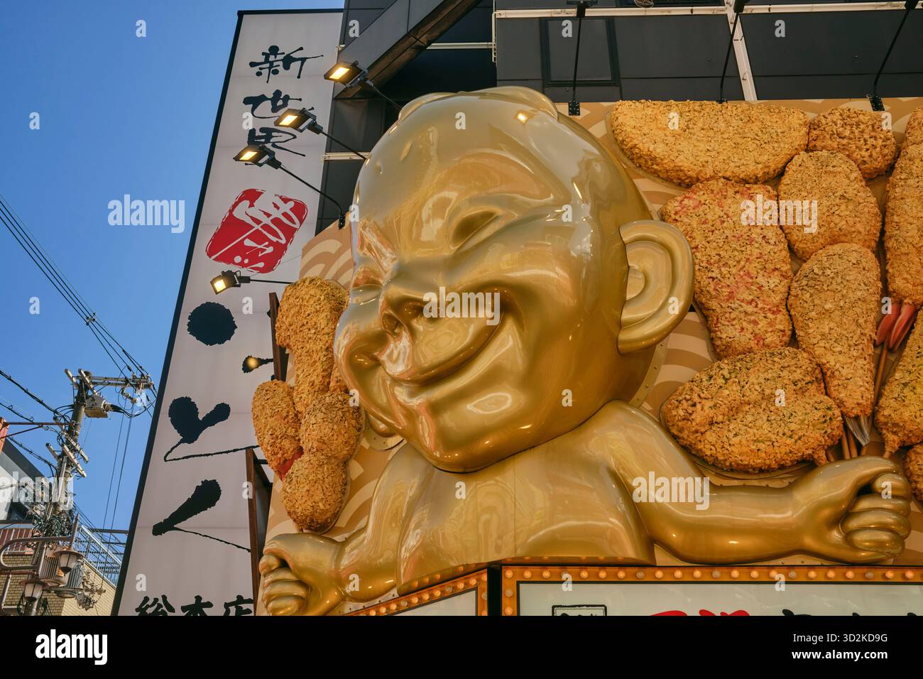 Die ikonische Billiken-Statue bewacht ein Kushikatsu-Restaurant mit frittierten Spießen in Shinsekai, das Glück und Osakas verspielten Geist symbolisiert Stockfoto