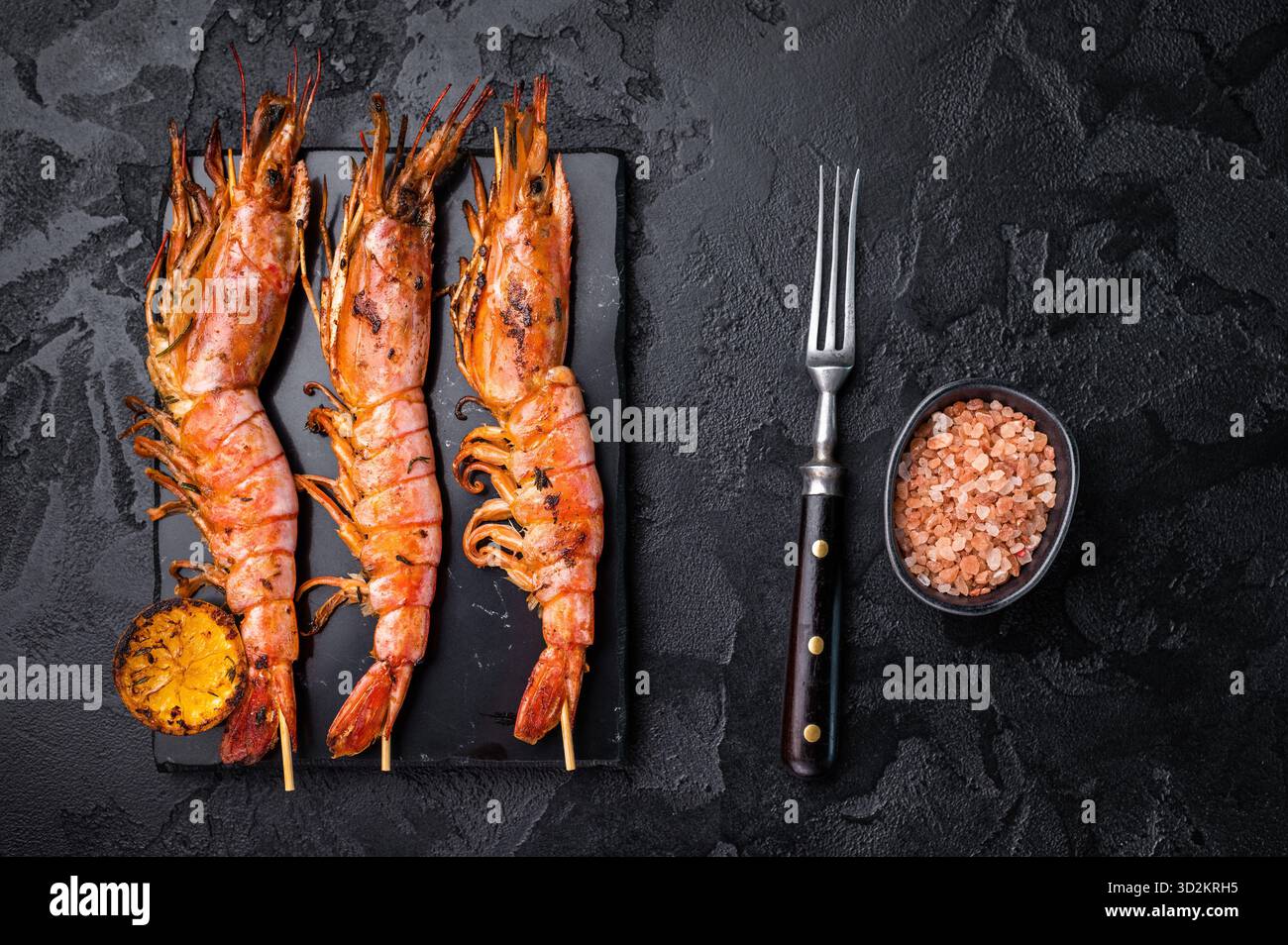 Garnelenkebab, Spieße mit gegrillten roten Garnelen Langostino Austral. Schwarzer Hintergrund. Draufsicht. Stockfoto