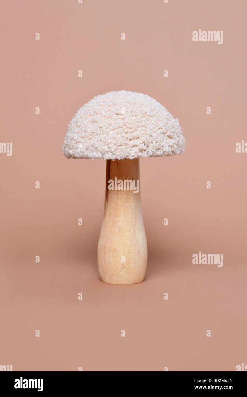 Einzelnes dekoratives Pilzobjekt aus Holz und Textil auf beigefarbenem Hintergrund Stockfoto