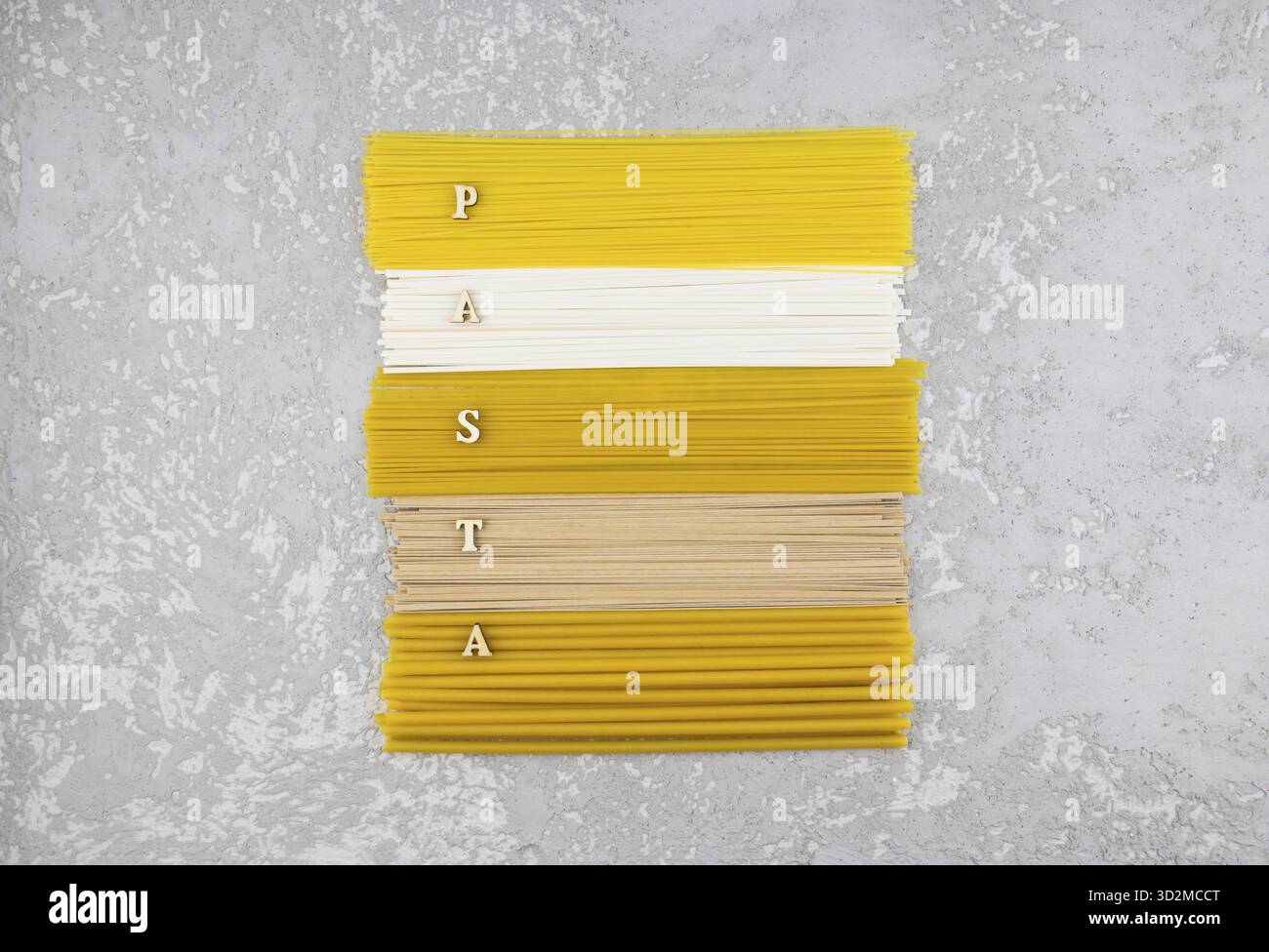 Blick von oben auf die langen Nudeln und Paghetti, die zusammen mit dem Wort der Holzbuchstaben - Pasta - gelegt wurden. Flache Lagen Stockfoto