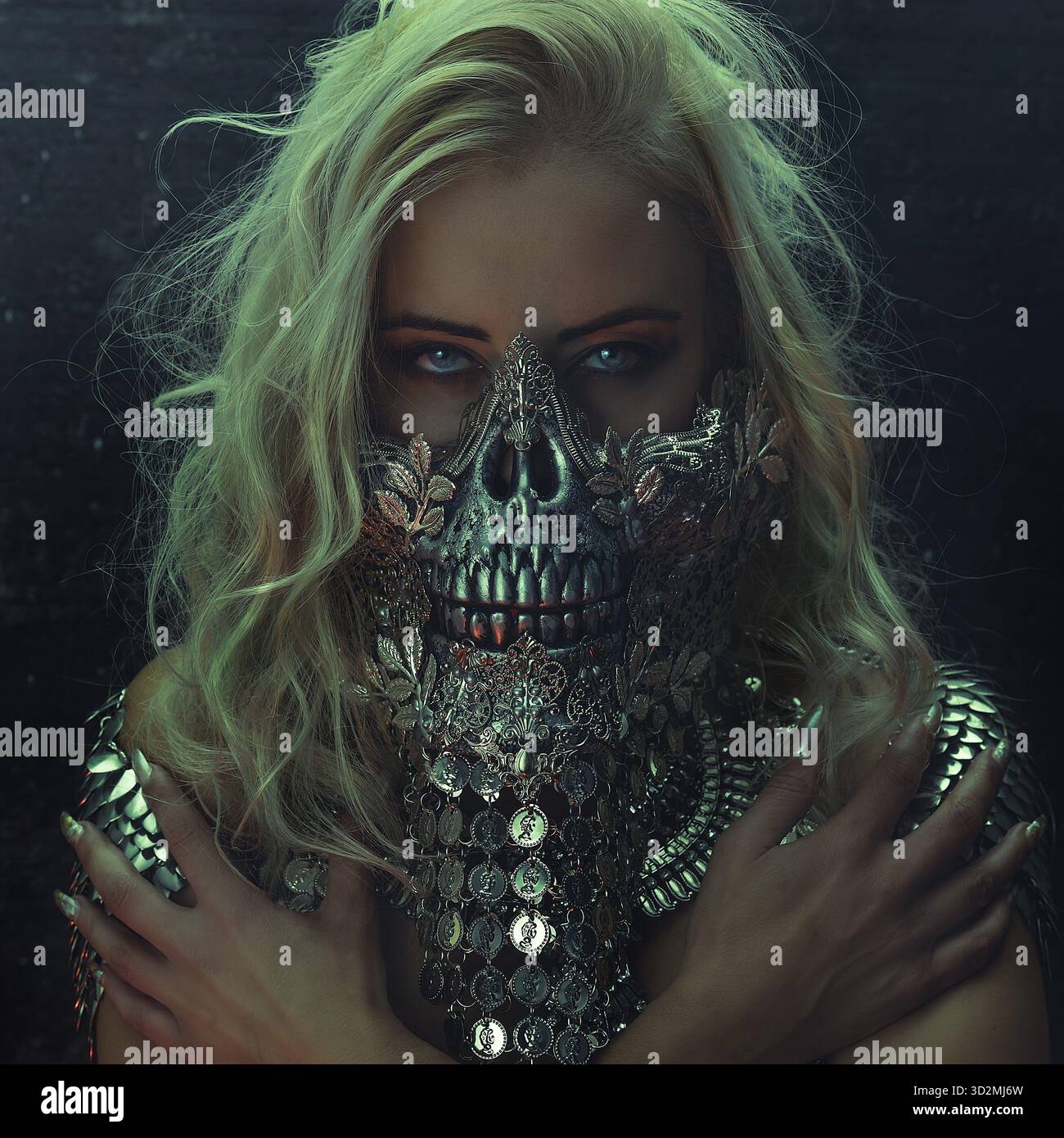 Schöne blonde Frau mit intensivem Look trägt eine silberne Maske mit Totenkopf und Metallteilen, halloween Stockfoto