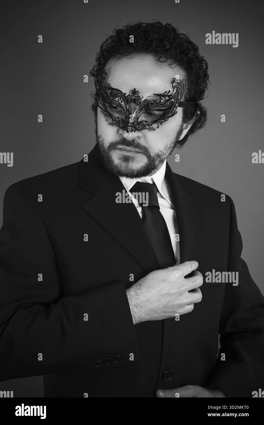 Verführerischer eleganter Geschäftsmann mit venezianischer Maske und schwarzem Anzug Stockfoto