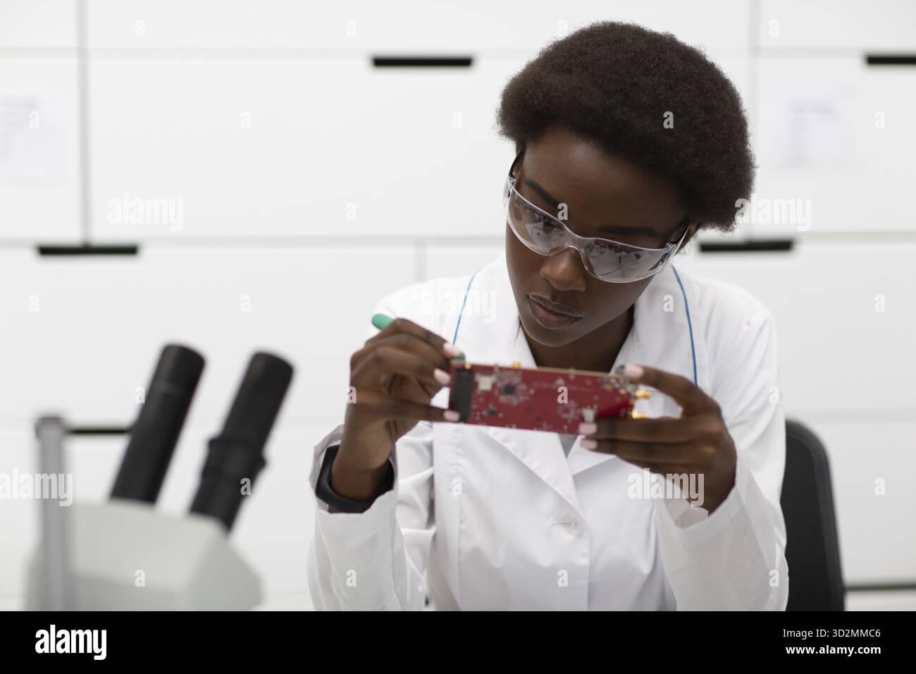 Wissenschaftlerin afroamerikanerin, die im Labor mit elektronischer Platine arbeitet. Forschung und Entwicklung durch die farbige schwarze Frau Stockfoto