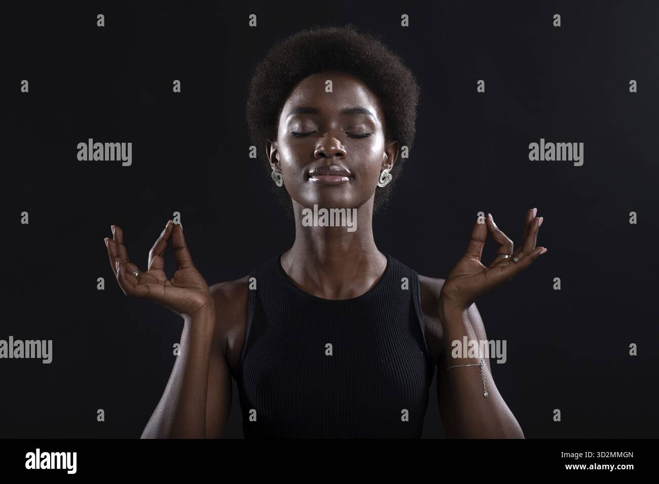 Das Studio hat ein Porträt eines afroamerikanischen weiblichen Models aufgenommen, das Zen-Yoga-Mudra oder OK-Zeichen zeigt. Frau meditiert auf schwarzem Hintergrund Stockfoto