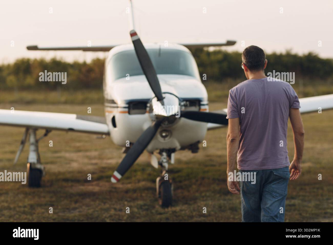 Pilot Mann, der neben einem kleinen Privatflugzeug läuft Stockfoto