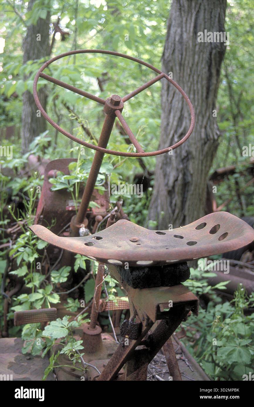Verrostetes Rad und eiserner Sitz eines amerikanischen Traktors um 1900, abgelegt in einem Waldgebiet, Marksboro, New Jersey, USA Stockfoto