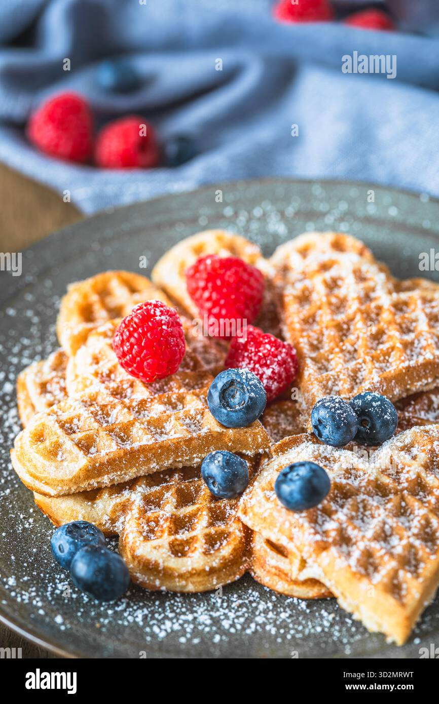 Hausgemachte Waffeln mit Puderzucker und Beeren Holztisch, vertikal Stockfoto