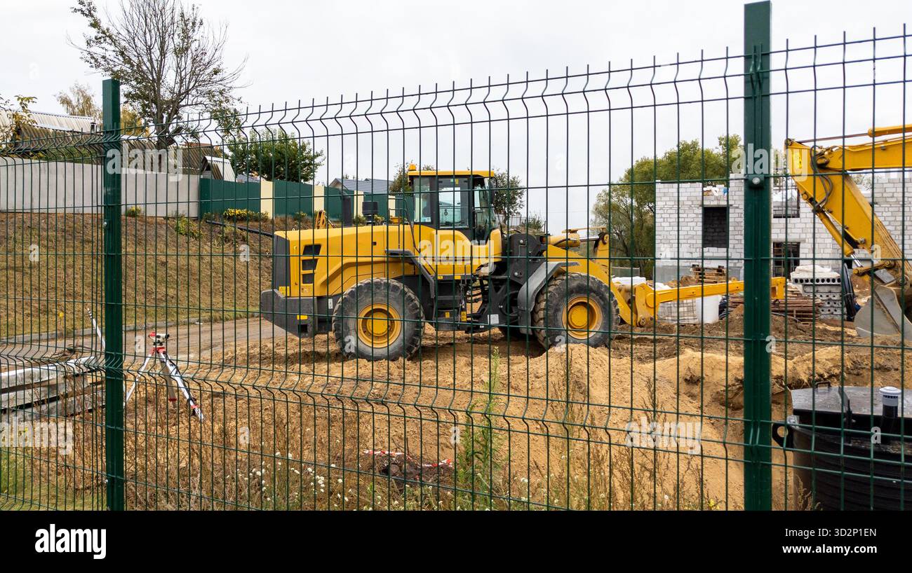 Orangener Bulldozer auf einer Baustelle an einem bewölkten Tag. Baumaschinen bewegen Sand während der Arbeit. Stockfoto