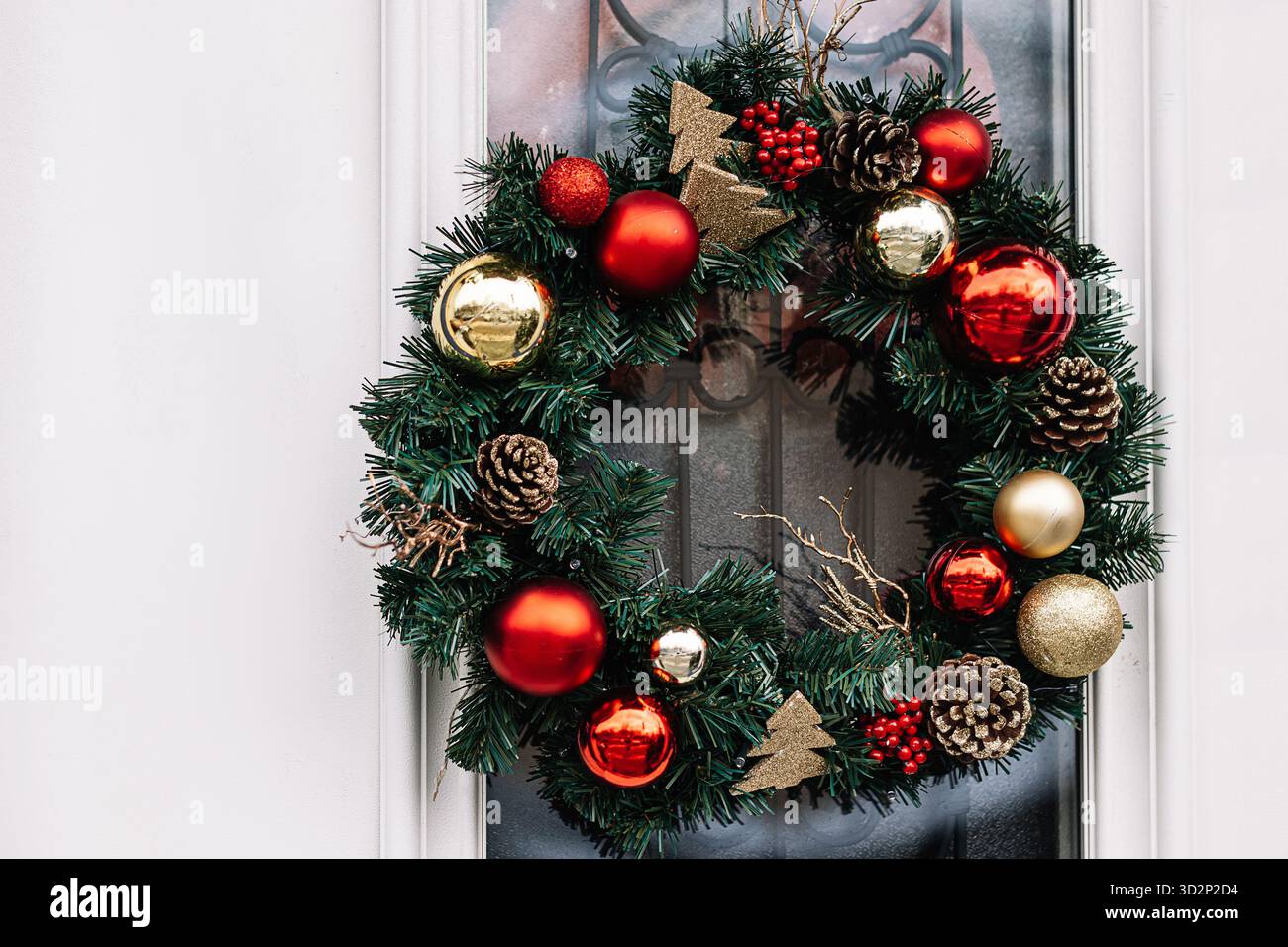 Weihnachtskranz an der Haustür. Festliche Wohndekoration. Dekor aus Weihnachtskugeln und Tannenzweigen. Stockfoto
