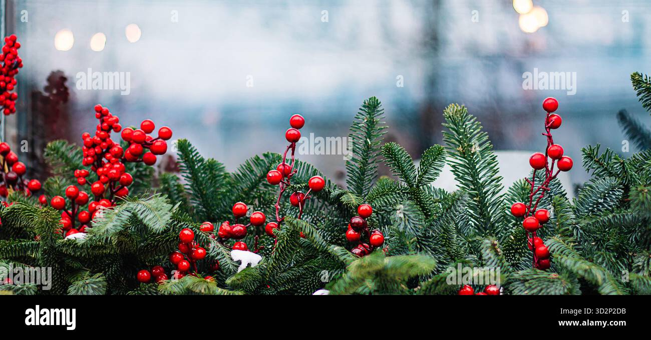 Weihnachtsdekoration am Fenster. Tannenzweige mit roten Beeren. Straßendekoration. Stockfoto