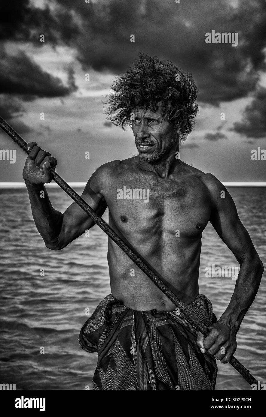Ein Höhlenmann steht stolz auf einem Floß in der Detwah Lagune in Socotra und zeigt einen einzigartigen Lebensstil vor einer bewölkten Kulisse. Stockfoto