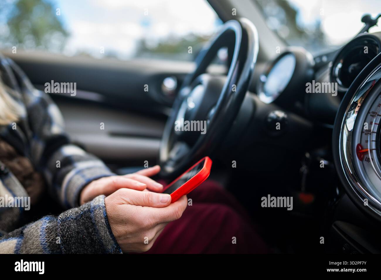 Autofahrerin, die online über das Smartphone in sozialen Medien scrollt, Nachrichten beantwortet, Nachrichten auf dem Telefon liest. Stockfoto