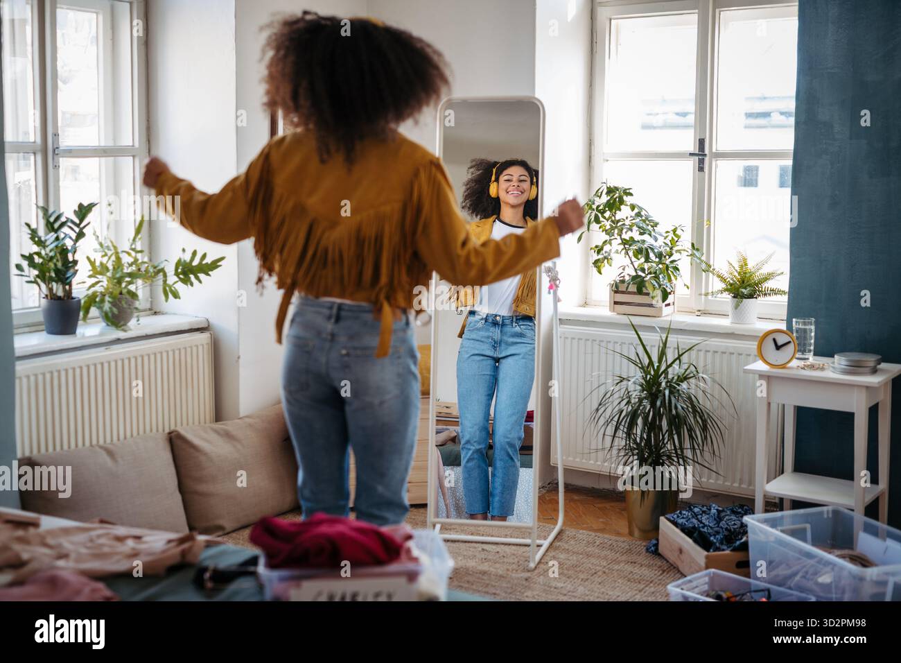 Junge Frau tanzt vor dem Spiegel mit Kopfhörern. Stockfoto