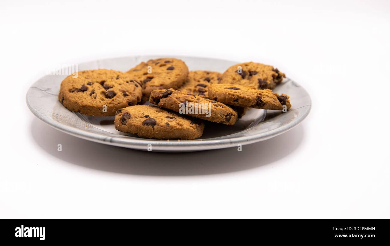 Frisch gebackene Schokoladen-Chip-Cookies auf einem Teller vor einem sauberen weißen Hintergrund angeordnet. Süßes Dessert oder Snackkonzept. Stockfoto