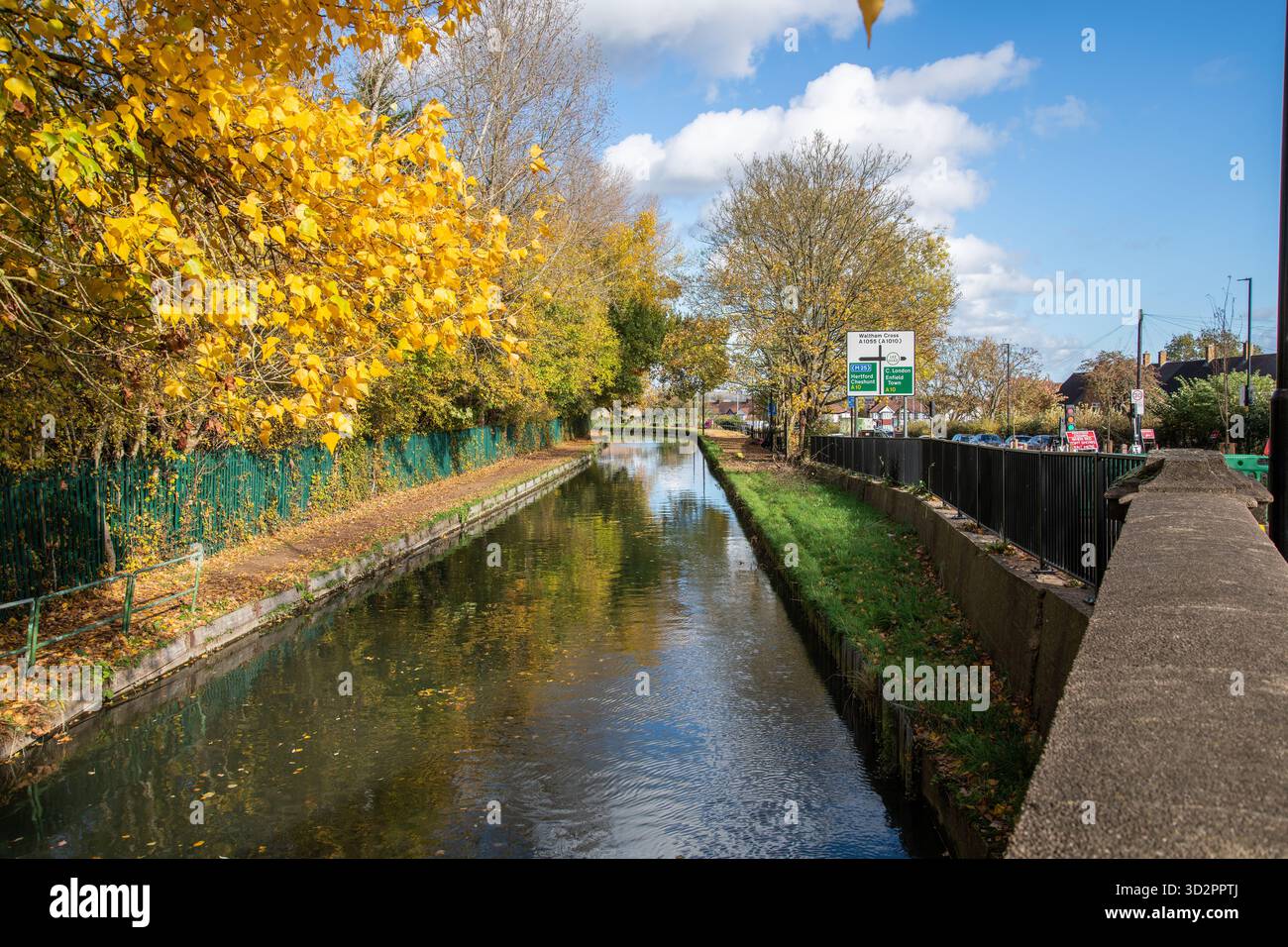 Malerischer Blick auf den New River bei Enfield mit Bäumen in leuchtenden Herbstfarben am Flussufer. Ruhige britische Landschaftsszene. Stockfoto