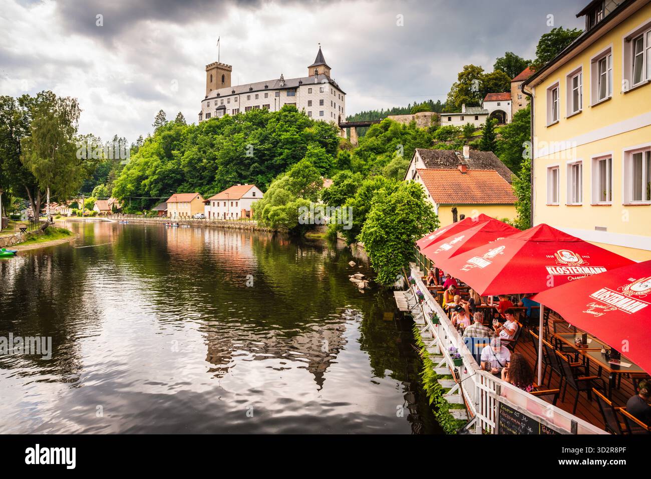 Café am Flussufer am Ufer des Flusses Vitava vor der Burg Rožmberk, einer der ältesten Schlösser in Tschechien. Stockfoto