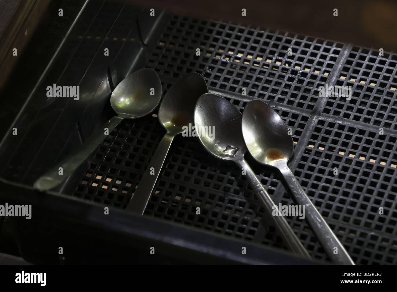 Glänzende silberne Löffel, Küchenutensilien aus Metall, reflektieren helldunkles, schwarzes Gitter. Jedes Besteck erscheint sauber und trägt zum Ordnungs- und Ordnungsgefühl bei Stockfoto