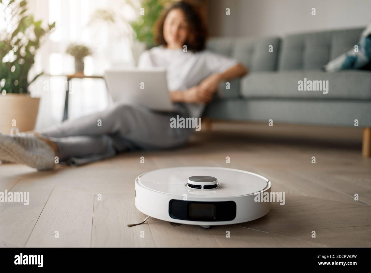 Weißer Roboter-Staubsauger auf Holzboden. Intelligente Reinigungstechnologie Stockfoto