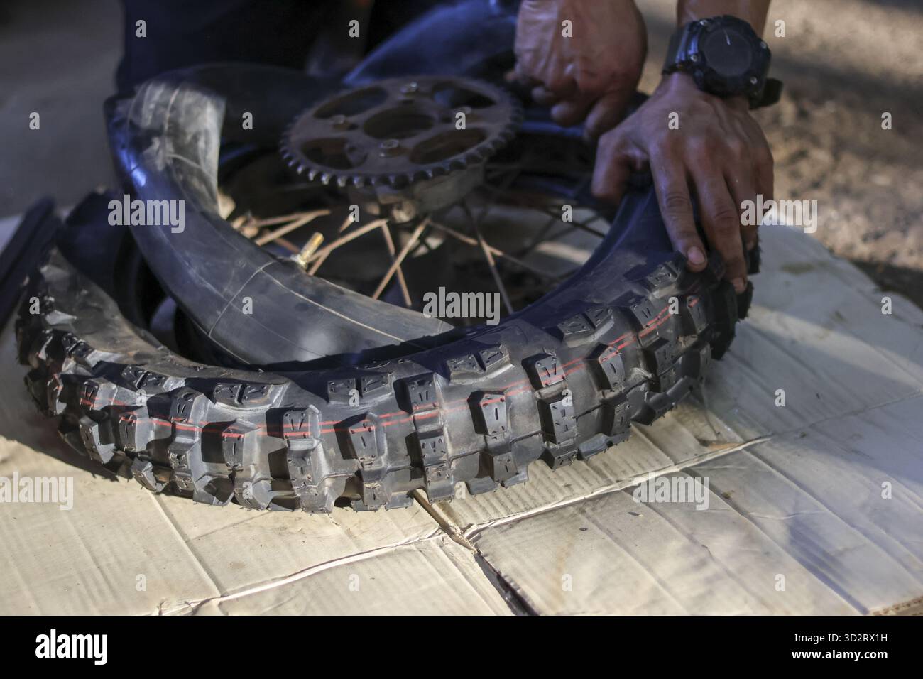 Fokussierte Einzelperson repariert sorgfältig platte Motorradreifen und entfernt vorsichtig beschädigte Innenschläuche für einen schnellen Austausch. Nahansicht erfasst Hände Stockfoto