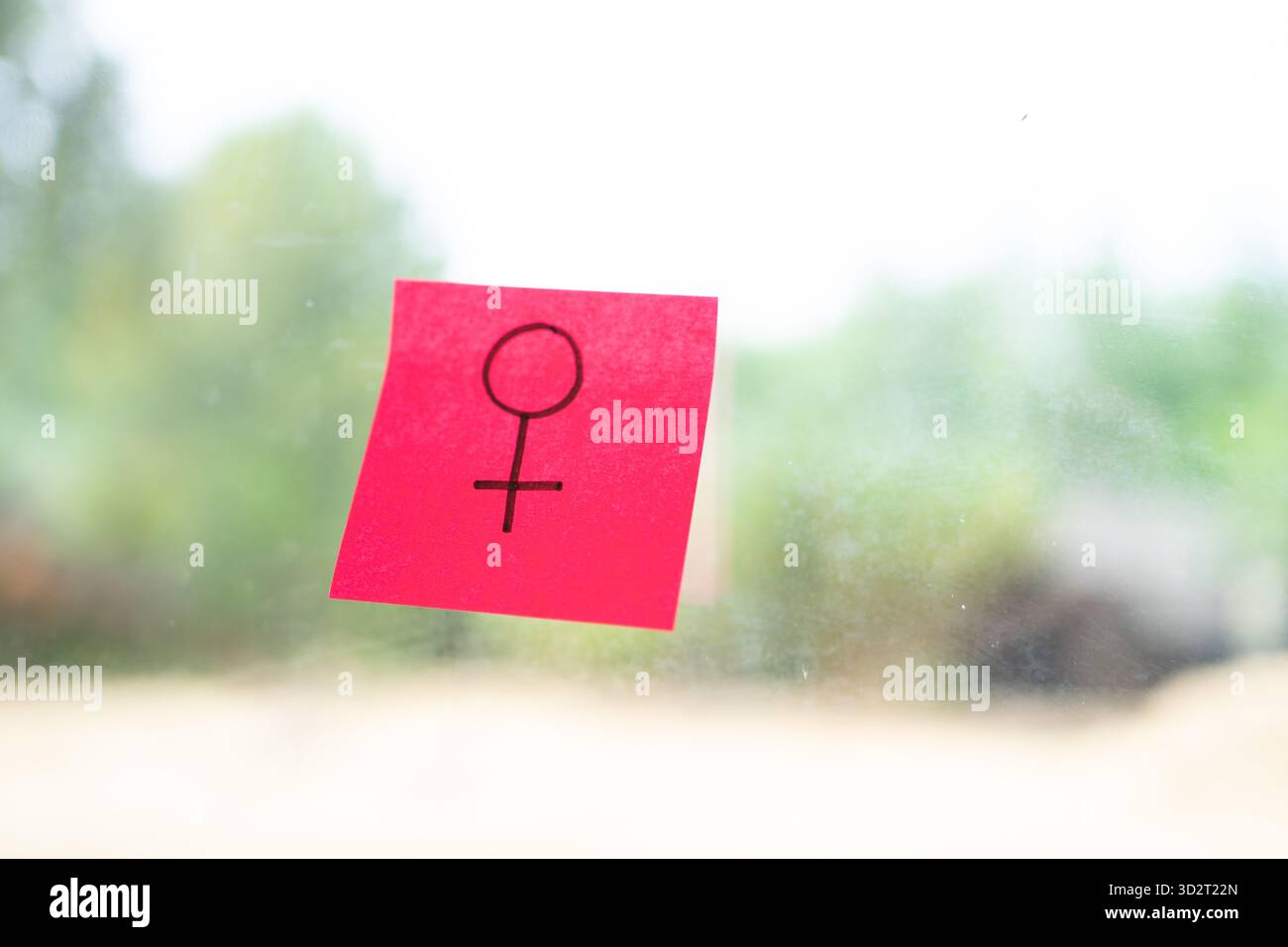 Haftnotiz mit einem weiblichen Geschlechtssymbol auf einem Glasfenster Stockfoto