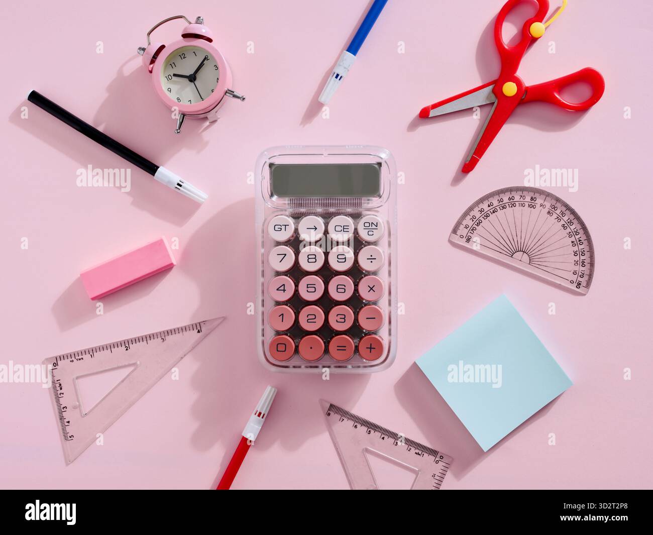 Schulpapier auf rosafarbenem Hintergrund einschließlich Taschenrechner, Lineale, Schere, Wecker und Stifte, ideal für Back-to-School-Aktionen Stockfoto