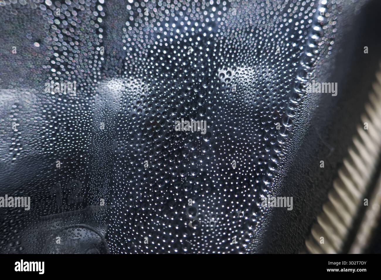 Ruhige Makroaufnahme der Kondensation von Wassertropfen. Feuchter Tau bildet sich auf dunkler abstrakter Hintergrundoberfläche. Erfrischendes Gefühl von Feuchtigkeit und reiner Flüssigkeit auf Glas Stockfoto