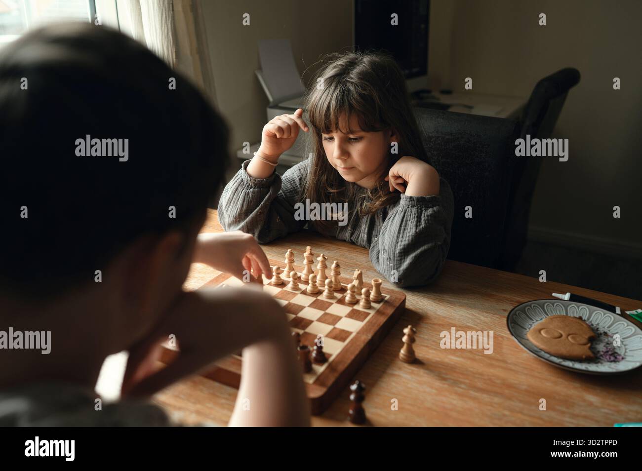 Kind Mädchen, das Schachbrett studiert und nachdenklich über ihren nächsten Zug entscheidet. Stockfoto