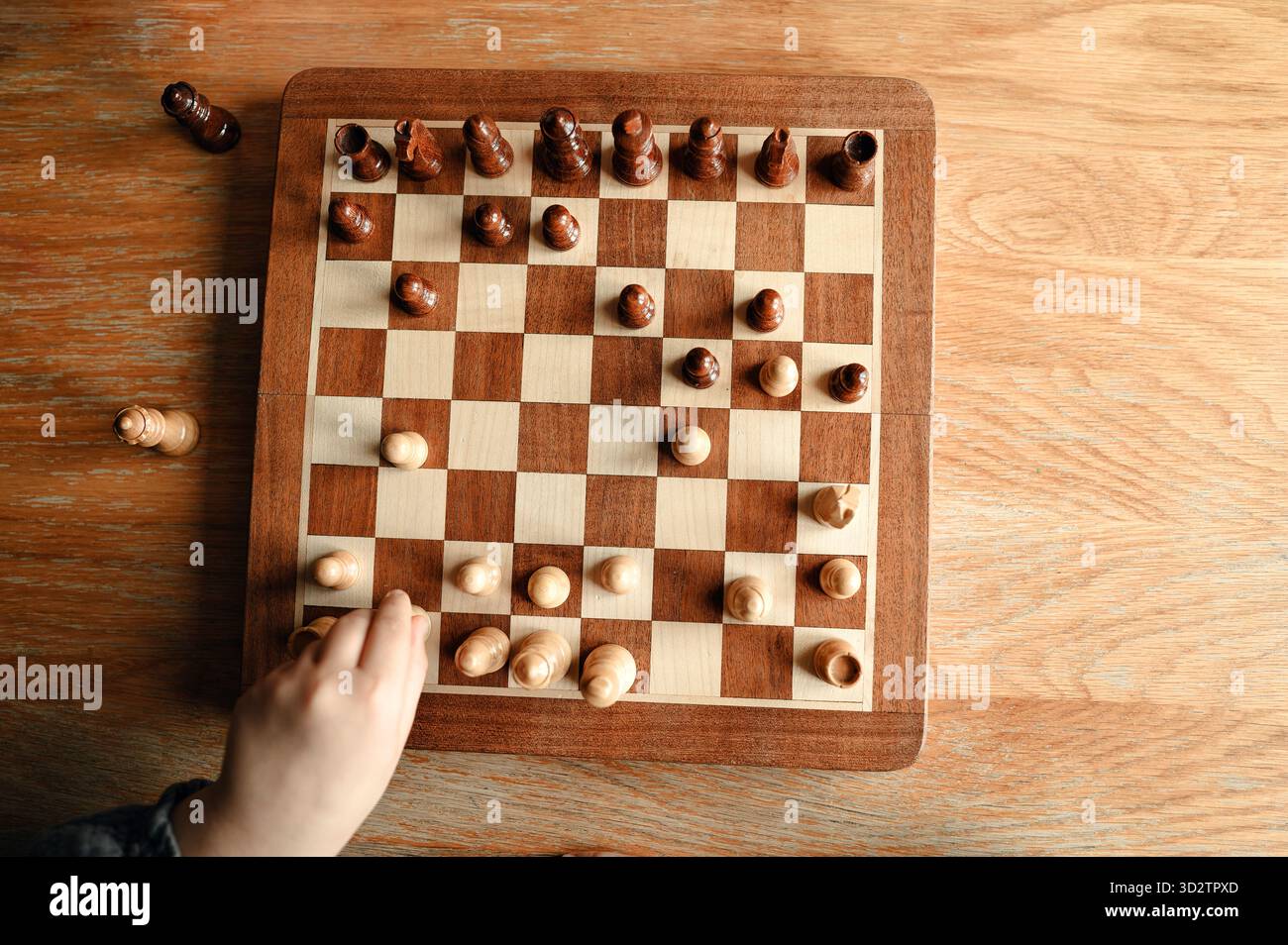 Schachbrett mit Stücken und Kinderhand. Stockfoto
