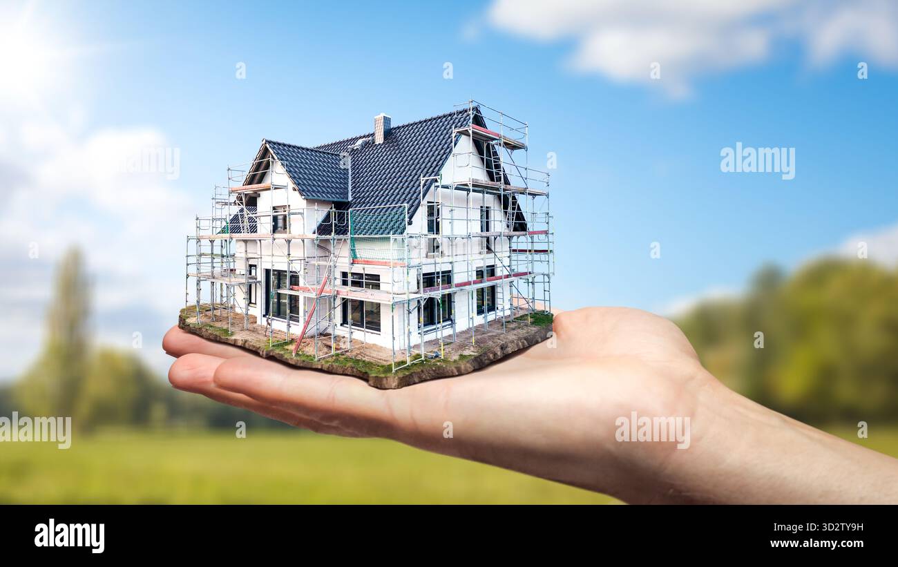 Die Hand hält ein maßstabsgetreues Modell eines im Bau befindlichen Hauses Stockfoto