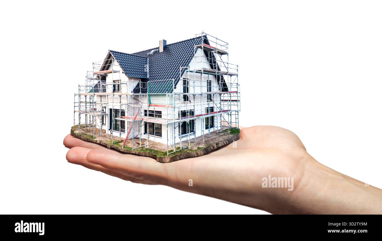 Die Hand hält ein maßstabsgetreues Modell eines im Bau befindlichen Einfamilienhauses Stockfoto