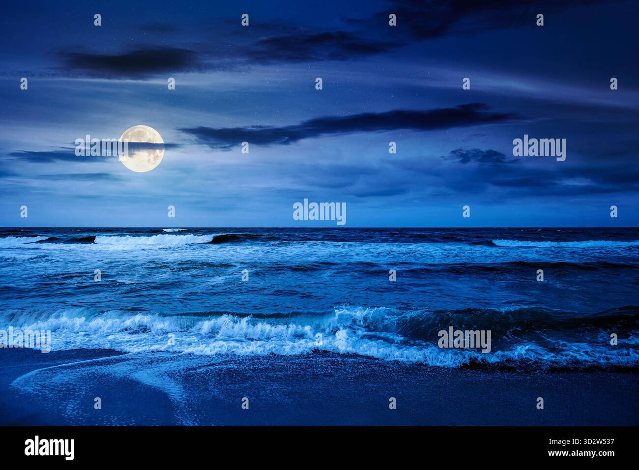 Schwarze Meereswellen stürzen nachts am Sandstrand. Sommerurlaub bei windigem Wetter unter dunklem bewölktem Himmel bei Vollmondlicht. Blick auf die dramatische Meereslandschaft. Stockfoto