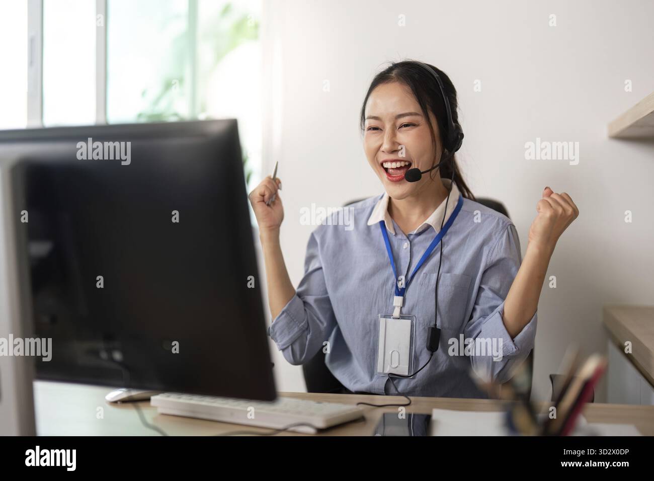 Eine freudige Kundenbetreuerin feiert Erfolge mit einem fröhlichen Ausdruck in ihrer Remote-Arbeitsumgebung Stockfoto