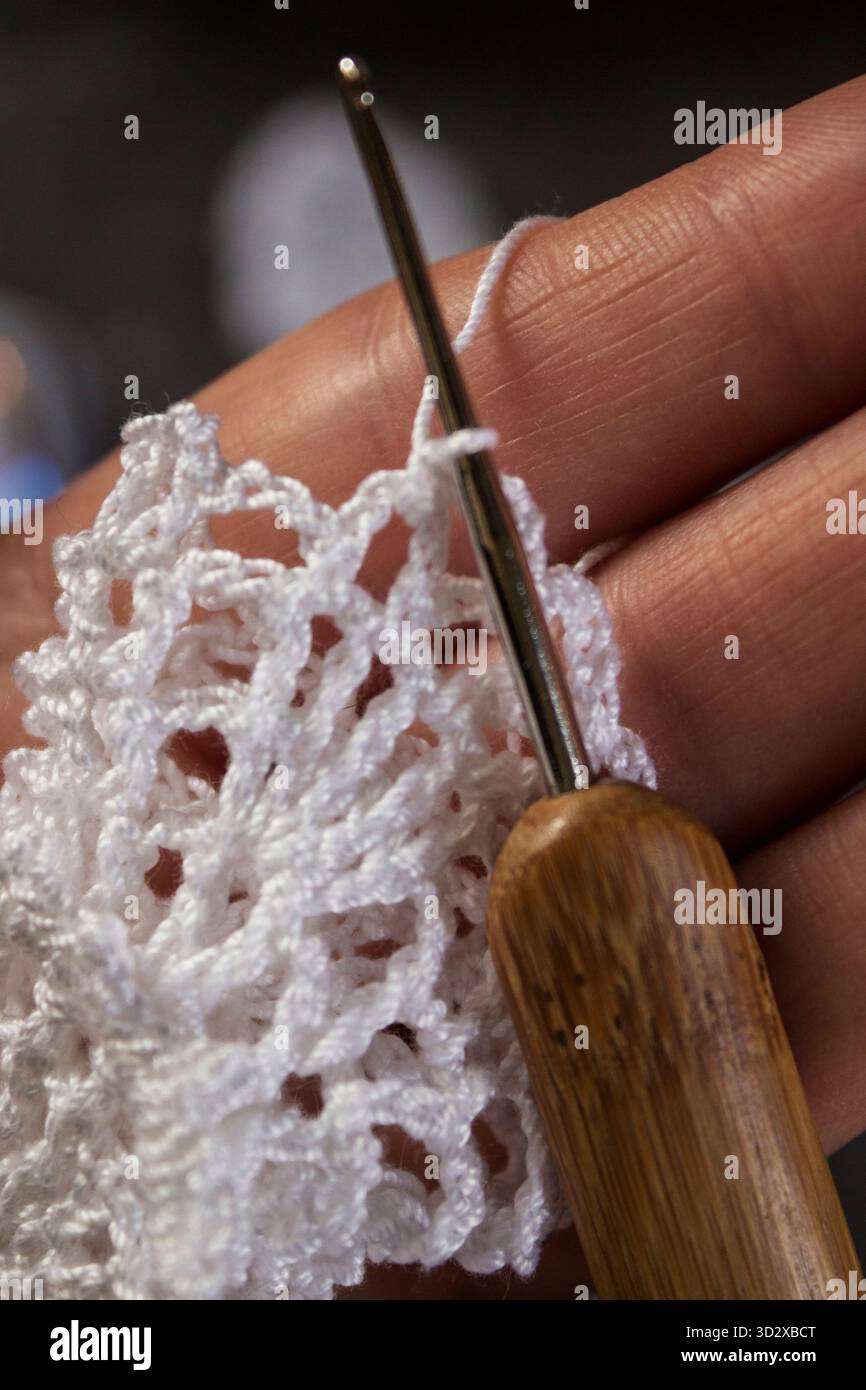 Nahaufnahme eines handgemachten weißen Weihnachtsengels, der mit einer Häkelnadel gemacht wird. Weihnachtsbasteln und DIY-Dekorationskonzept. Stockfoto