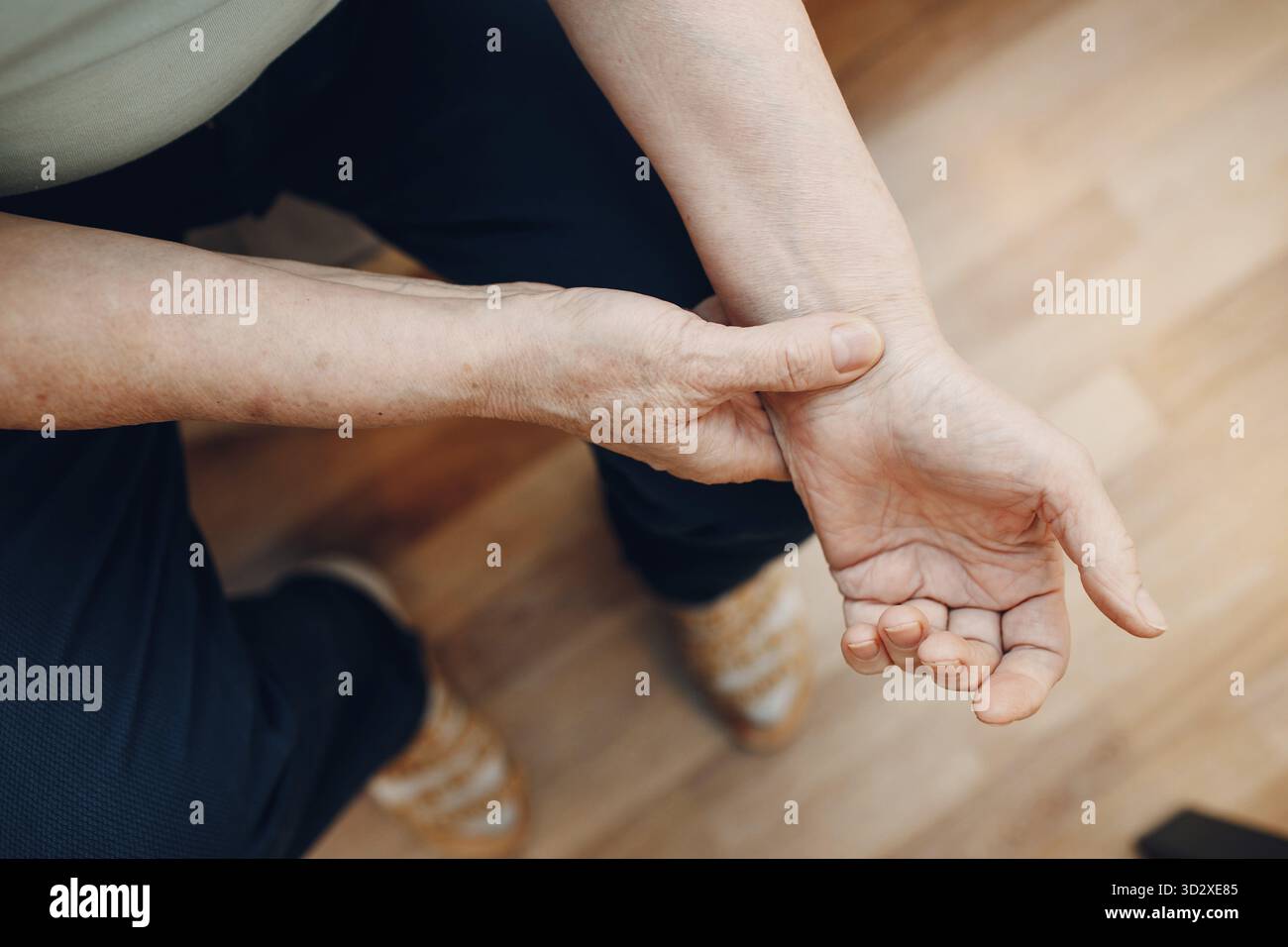 Weibliche alte Hand, die ihren eigenen Armpuls misst. Herzgesundheit der Seniorin Stockfoto