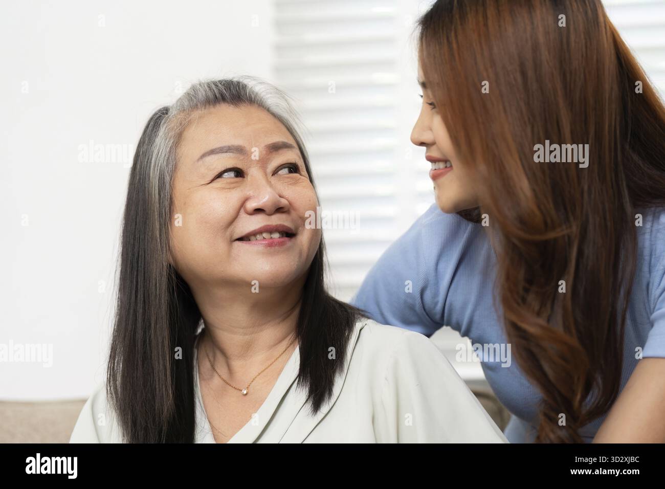 Eine Tochter teilt ein warmes Lächeln mit ihrer Mutter und betont ihre starke Bindung und emotionale Verbindung Stockfoto