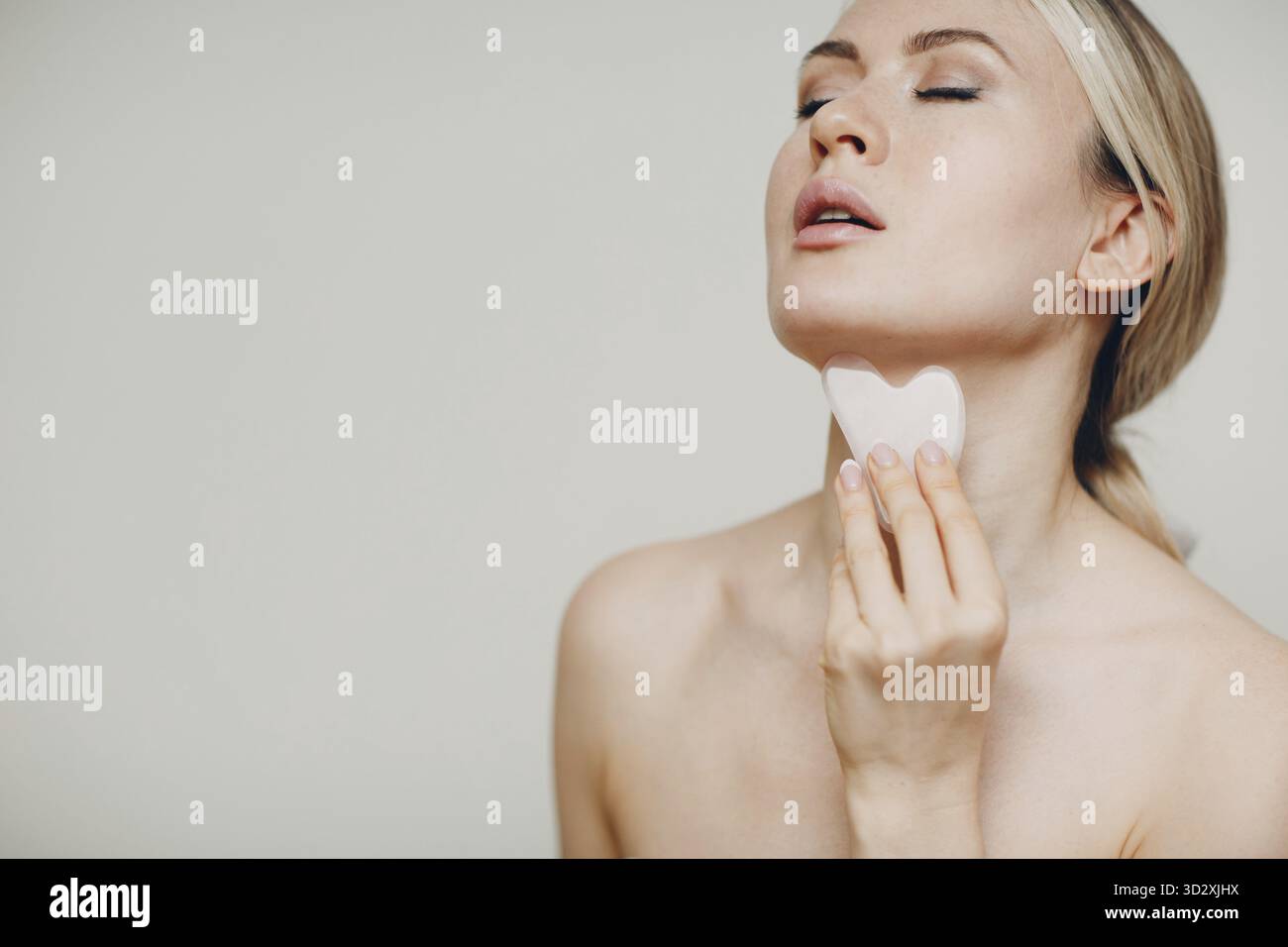 Junge Erwachsene Frau tun Gesicht guasha Behandlung Massage Verfahren Stockfoto