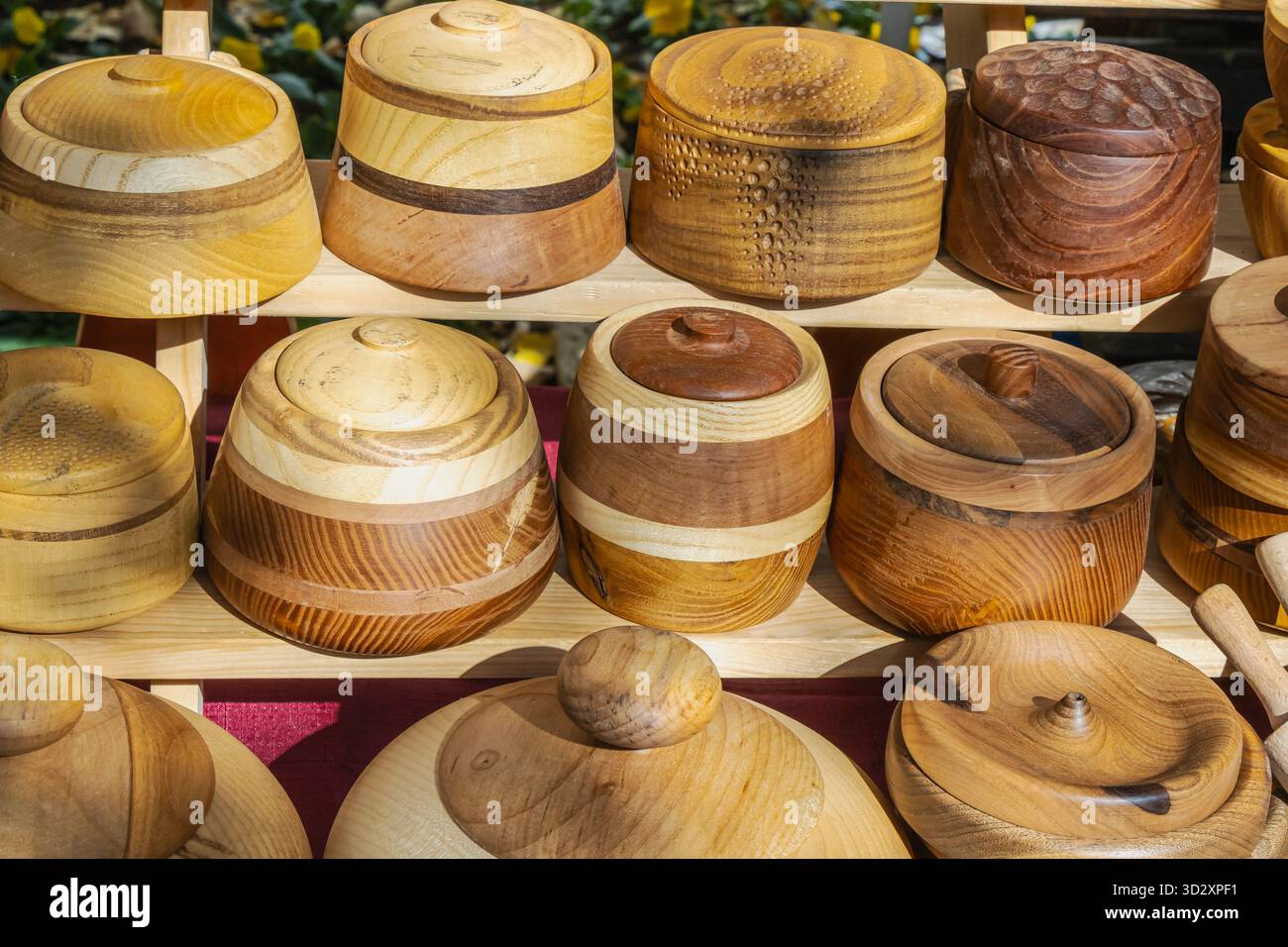 Eine Sammlung von handgefertigten Holzschalen und -Behältern mit einzigartigen Texturen und Mustern, die auf einem handwerklichen Markt ausgestellt werden. Die natürlichen Holztöne und craf Stockfoto