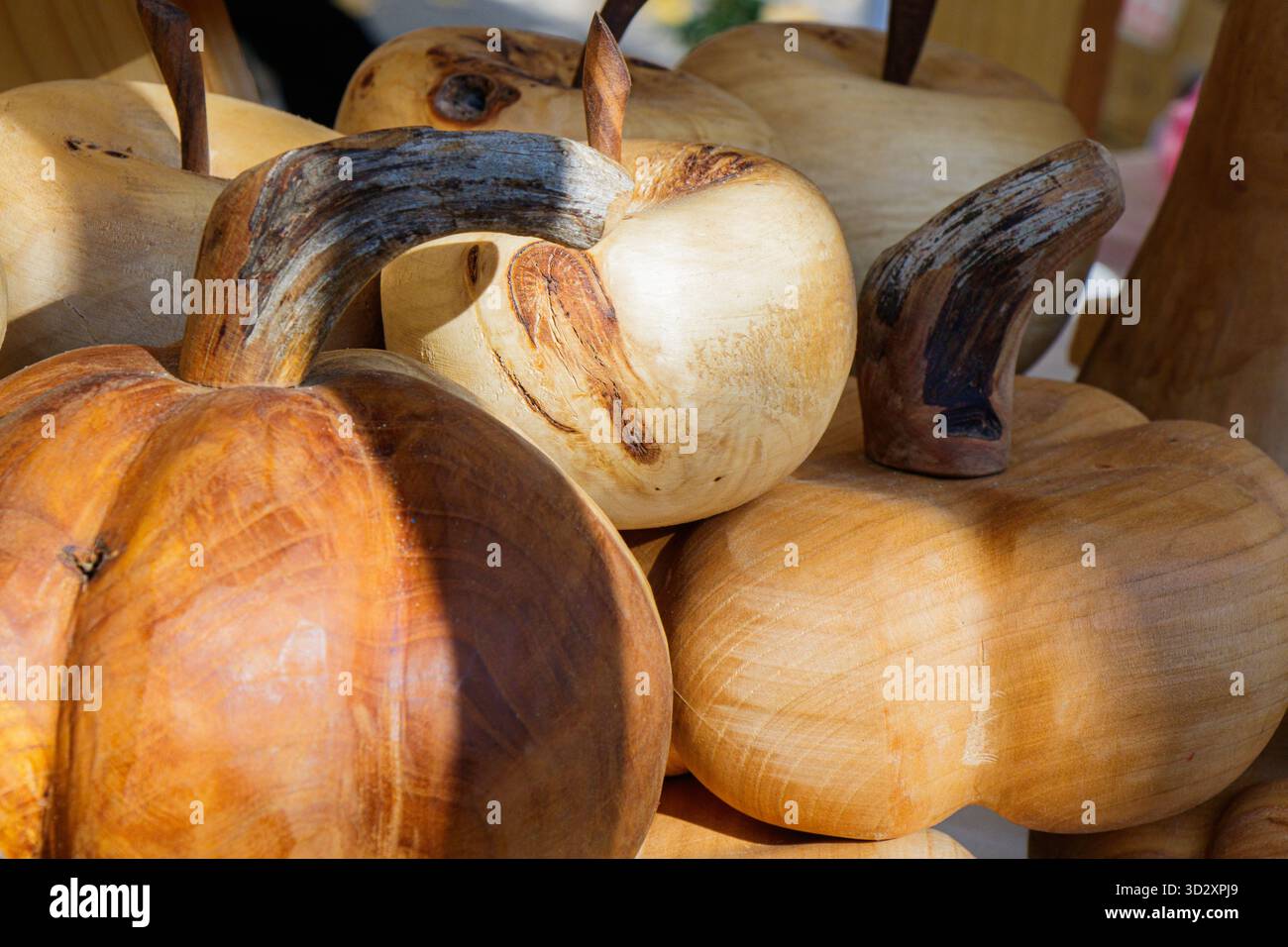 Nahaufnahme von handgefertigten hölzernen Kürbissen, die auf einem lokalen Herbstmarkt ausgestellt werden. Die warmen Töne, die natürlichen Körnungen und die organischen Formen betonen Tradi Stockfoto