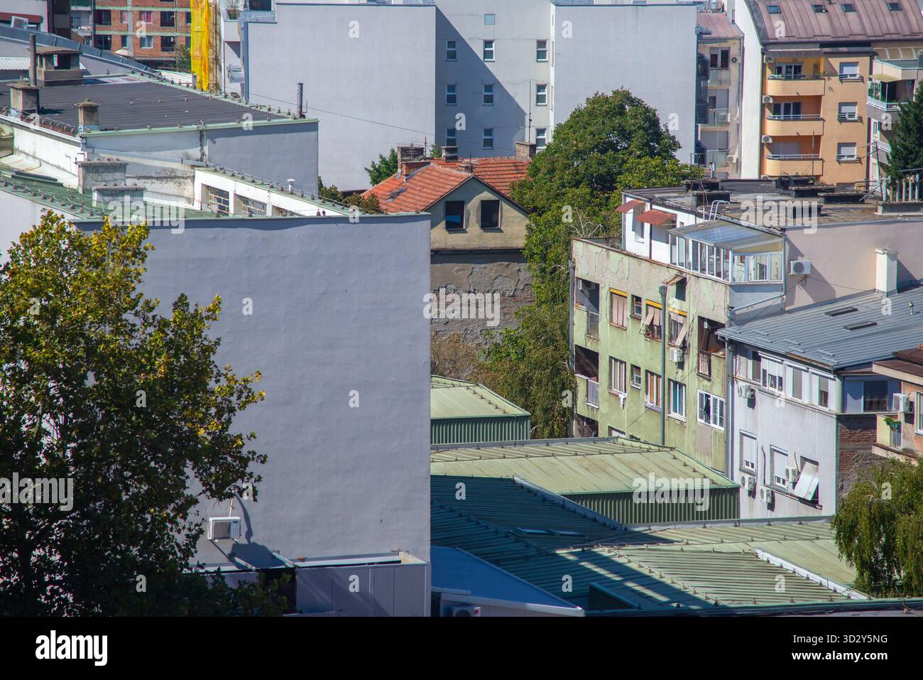 Urbane Szene in Belgrad, Serbien, zeigt eine Mischung aus älteren und neueren Wohnhäusern mit verblassten Fassaden, grünen Dächern und einem kleinen Haus mit einem Stockfoto