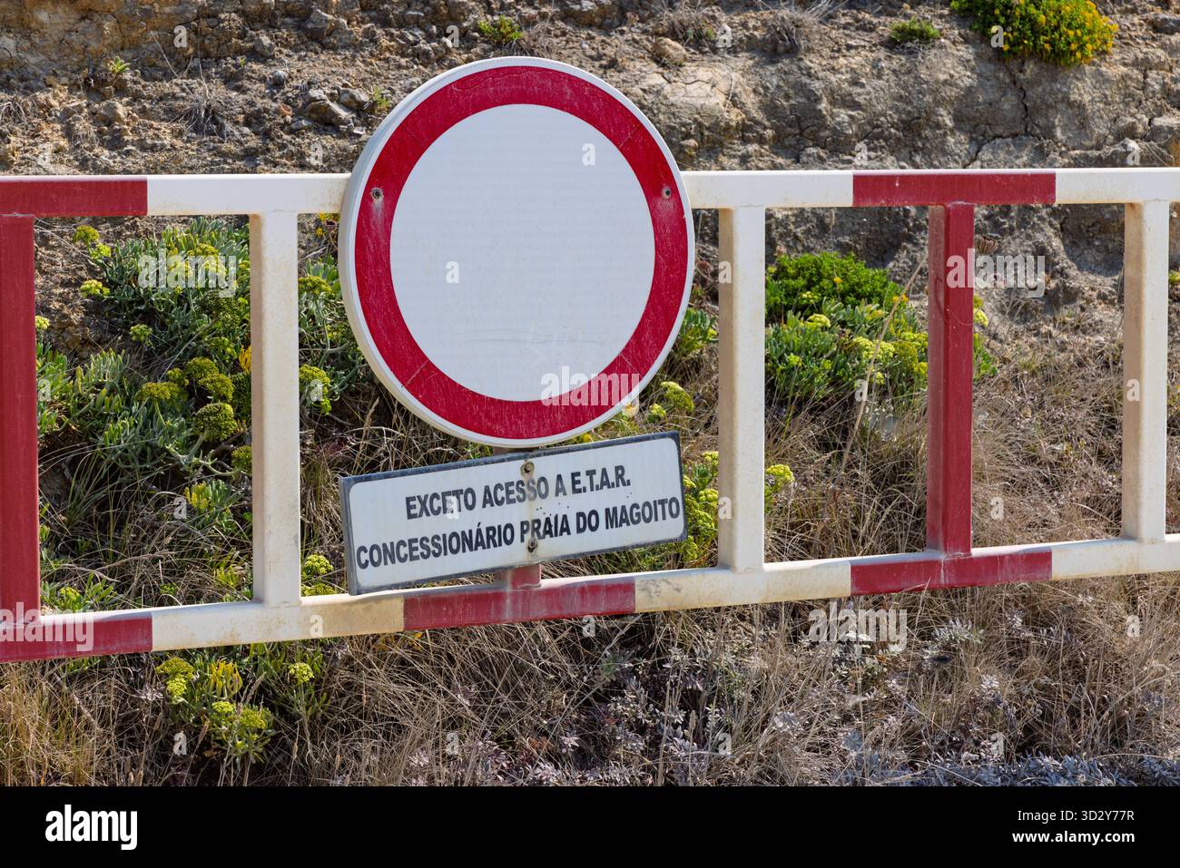 Barriere mit einem Schild „No Entry“ (kein Zutritt) in Praia do Magoito, Portugal, auf Portugiesisch, mit Hinweis auf eingeschränkten Zutritt außer für autorisierte Fahrzeuge (E.T.A.R. und Stockfoto