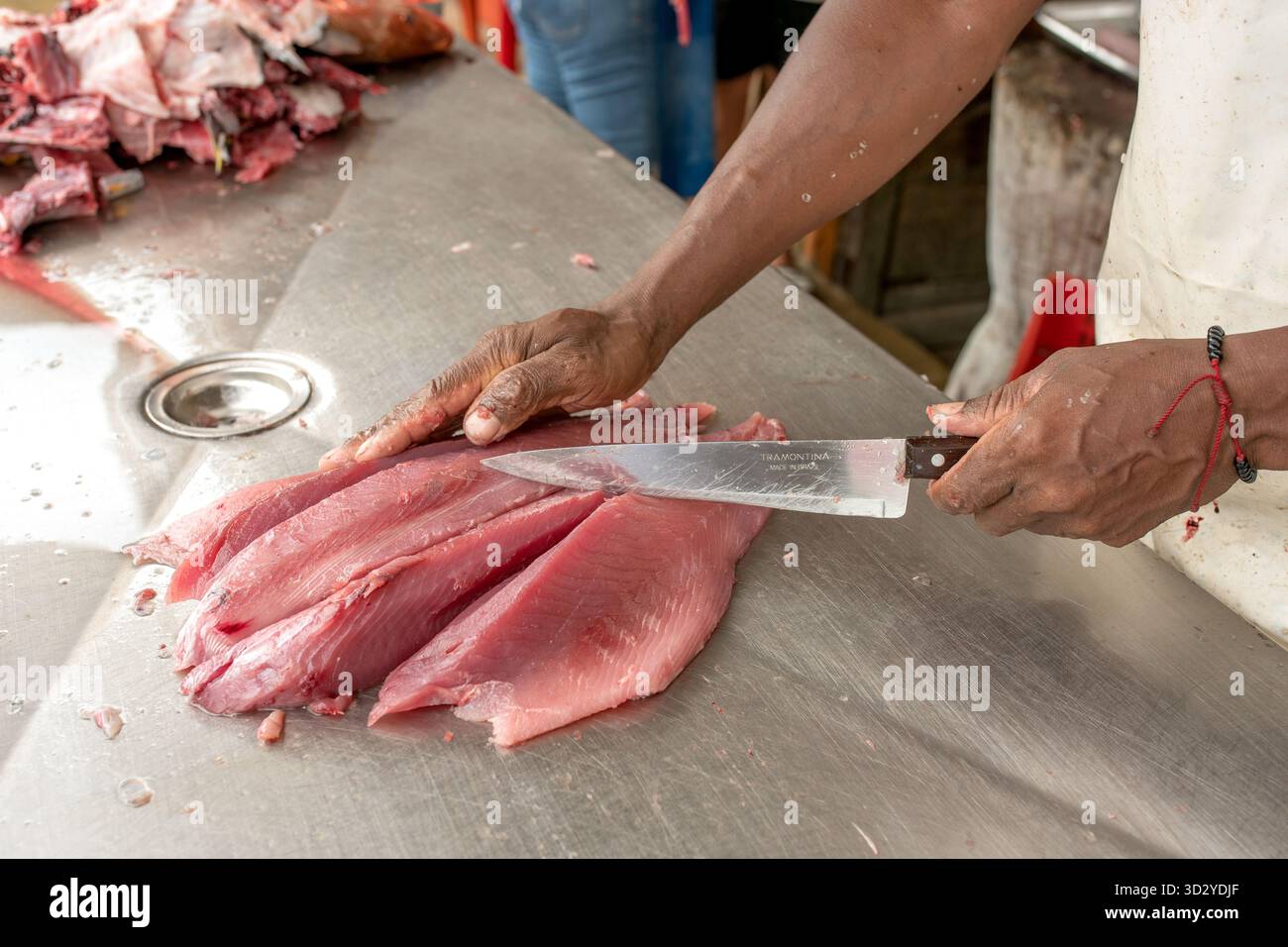 Mann filetiert frischen Fisch auf einem Tisch, traditionelle Fischzubereitung und kulinarische Meisterschaft. Schneiden von Verrundungen mit einem scharfen Messer auf einem lokalen Markt. Seafo Stockfoto