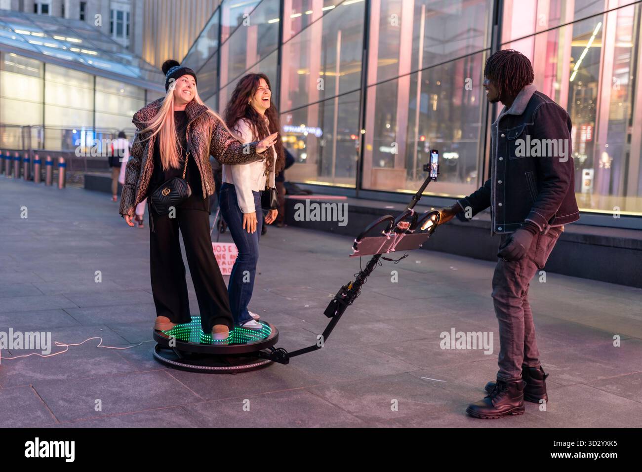 London, Großbritannien, 23. November 2025, zwei glückliche Frauen posierten für ein Zeitlupenvideo auf einer 360-Grad-Fotoplattform. Stockfoto