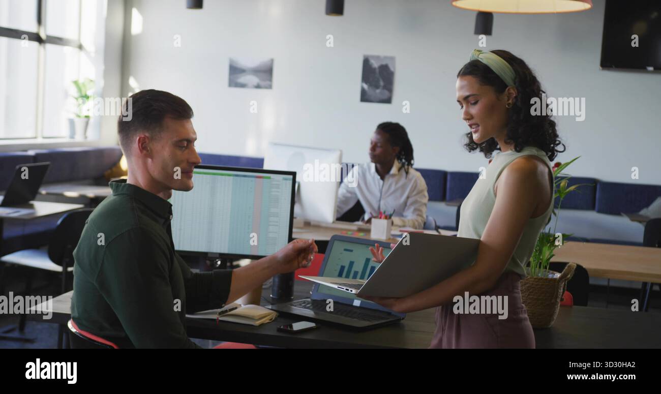 Prüfung von zwei Kollegen, die Datendiagramme im Coworking Office mit Laptops vergleichen Stockfoto
