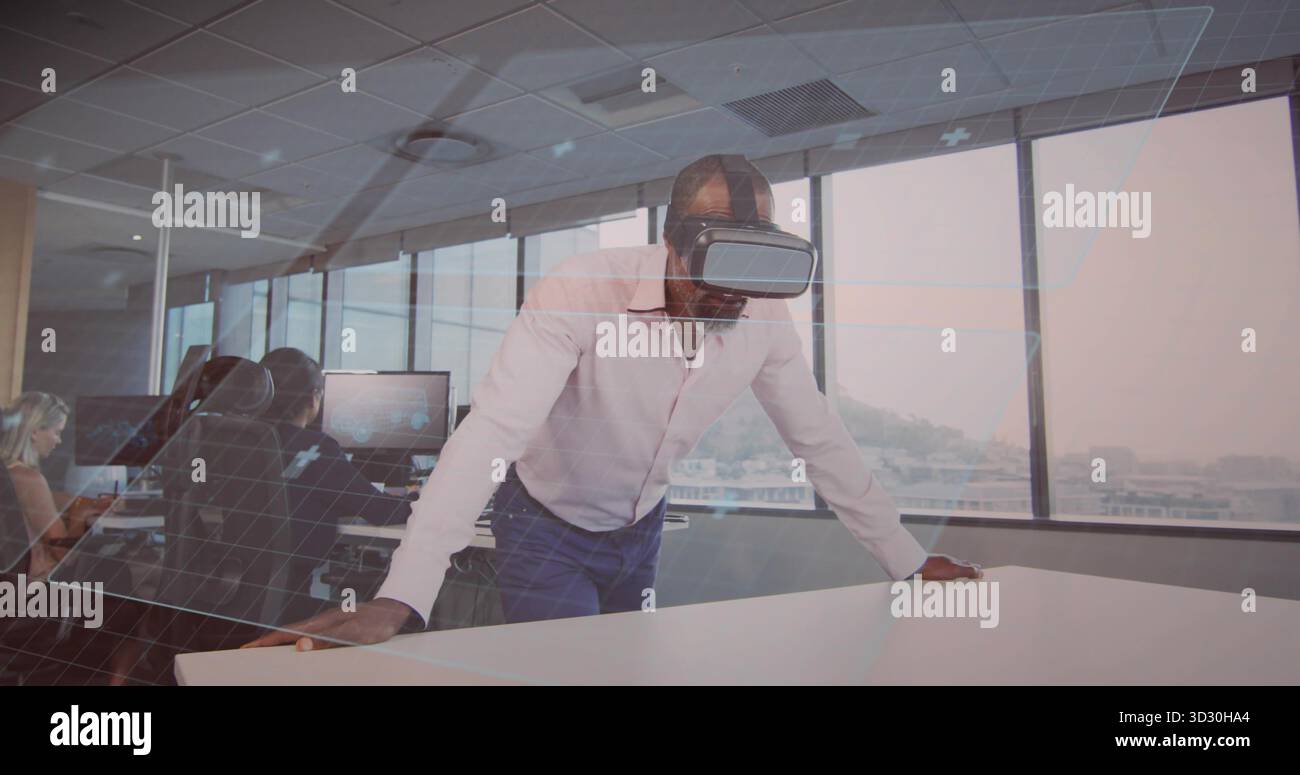 Nach vorne gelehnter afroamerikanischer Mann testet VR-Simulation am Konferenztisch im Büro, mit Headset Stockfoto