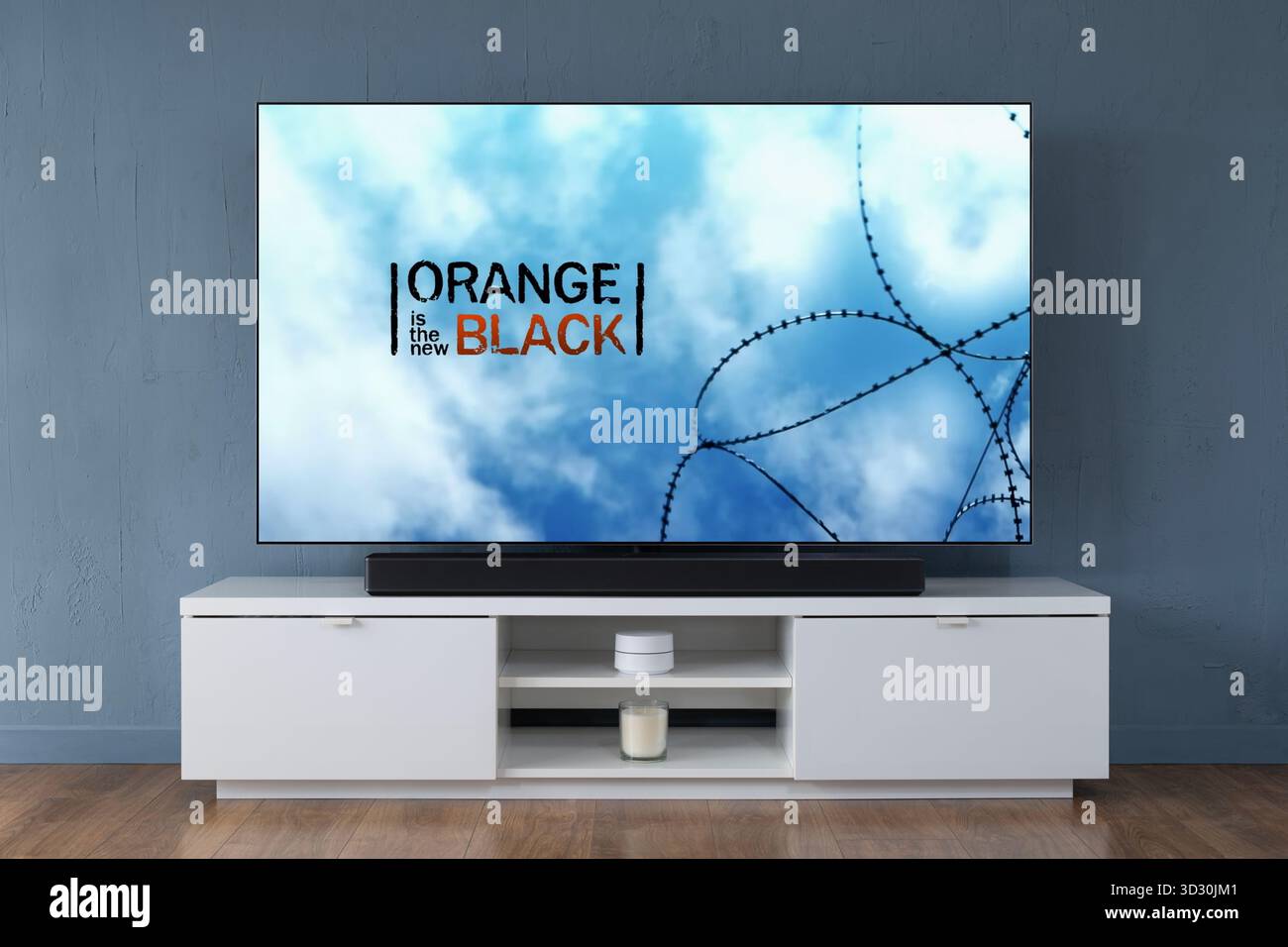 Ein Breitbild-OLED-Fernseher, der die Intro-Szene zur TV-Serie Orange zeigt, ist der New Black, der in einem modernen Wohnzimmer zu sehen ist. Stockfoto