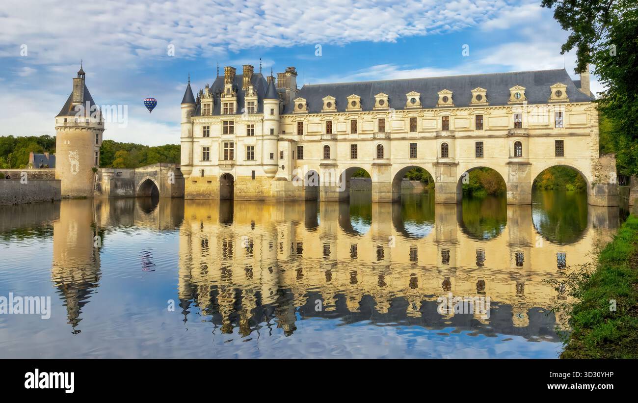 Ein atemberaubendes Chateau de Chenonceau erhebt sich majestätisch über einem reflektierenden Cher River und schafft ein symmetrisches Bild. Der blaue Himmel und verstreute cl Stockfoto