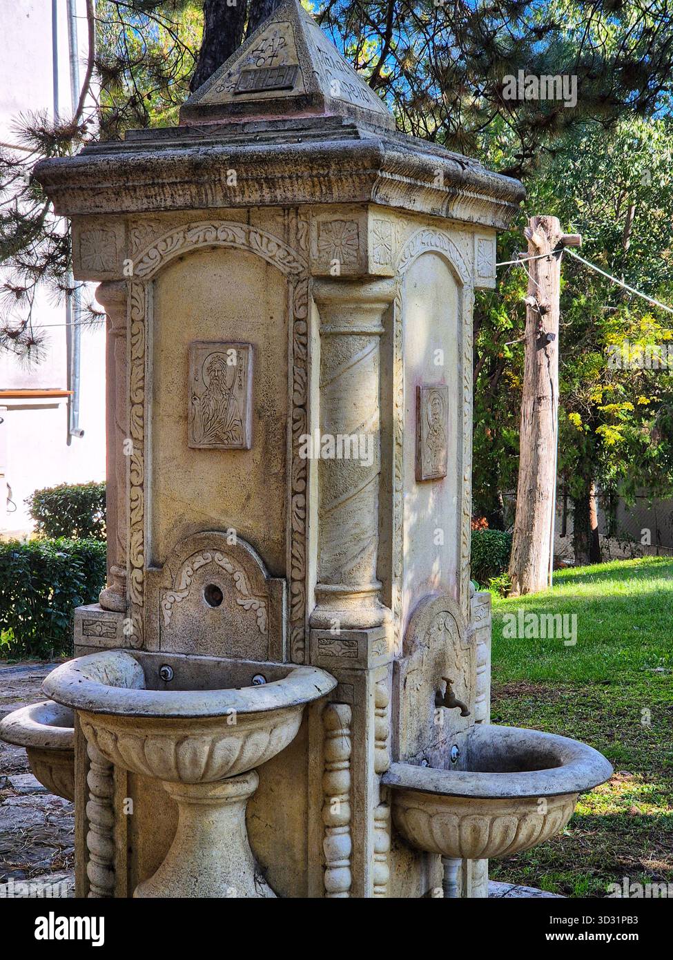 Quelle der Gnade. Ein Ort der Weihe und des reinen Wassers im Innenhof einer Kirche oder eines Klosters - Smartphone-aufgenommenes Stockfoto