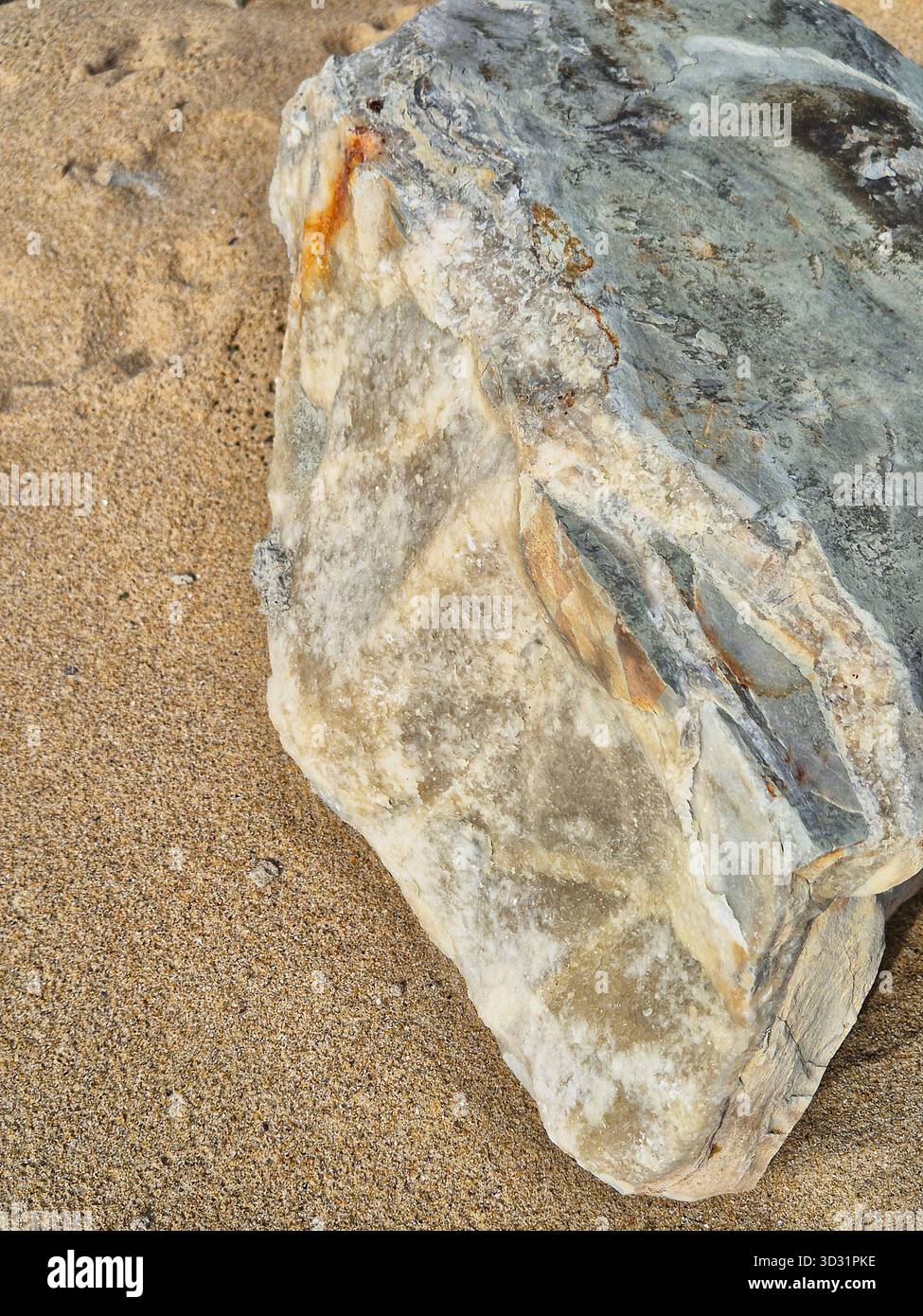 Felsen und Küste. Weißer Felsbrocken auf dem Sand eines bulgarischen Strandes. Nahaufnahme von Felsen auf Strandsand. Geologische Details an der Schwarzmeerküste - Smartphone-aufgenommenes Stockfoto