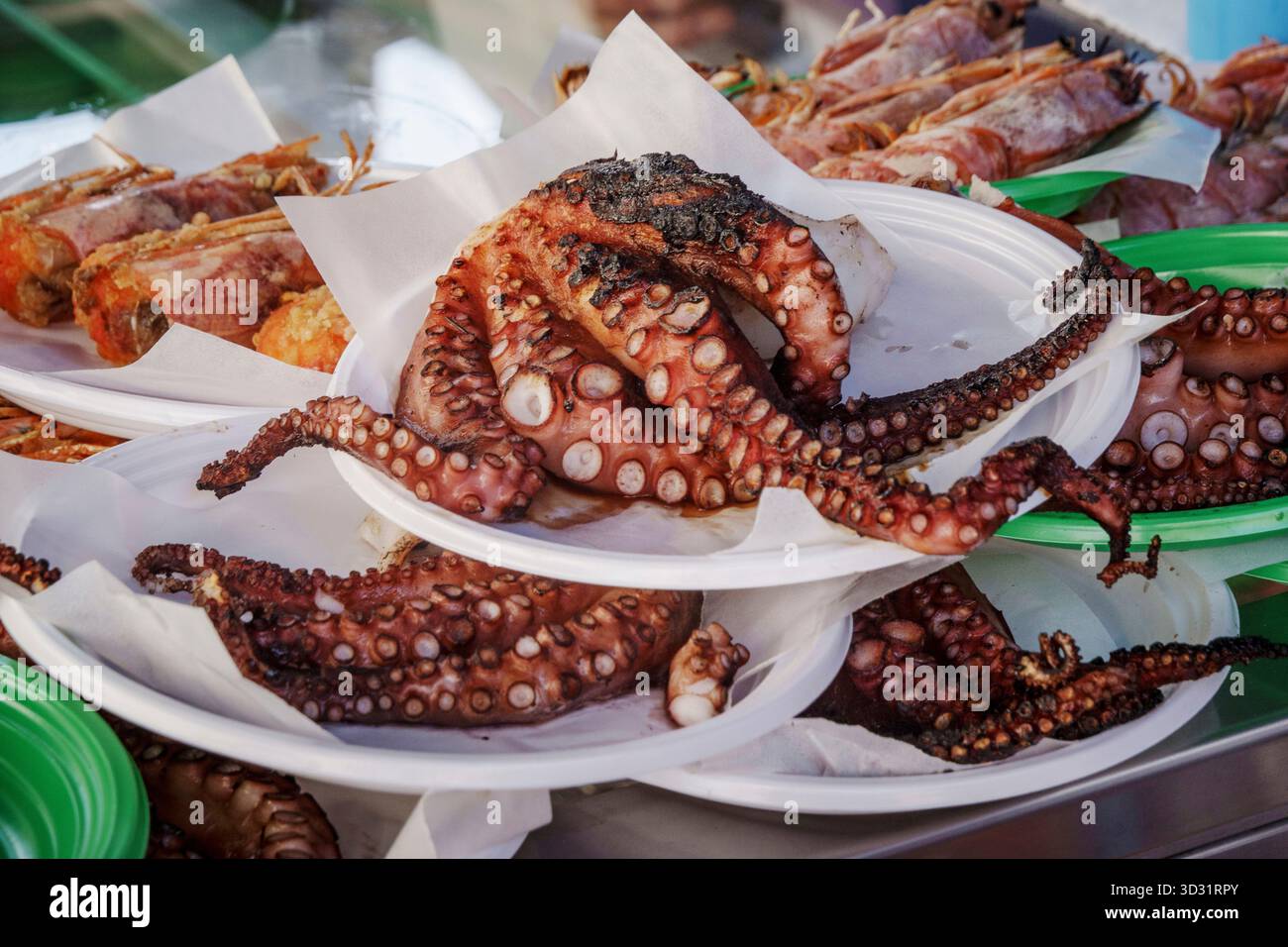 Eine Nahaufnahme eines ganzen Tintenfisches vom Saibling, einer traditionellen mediterranen Streetfood-Delikatesse, serviert auf einem Papierteller auf einem Markt im Freien. Stockfoto